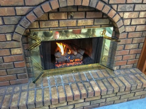 Gas logs installed in masonry fireplace with glass doors