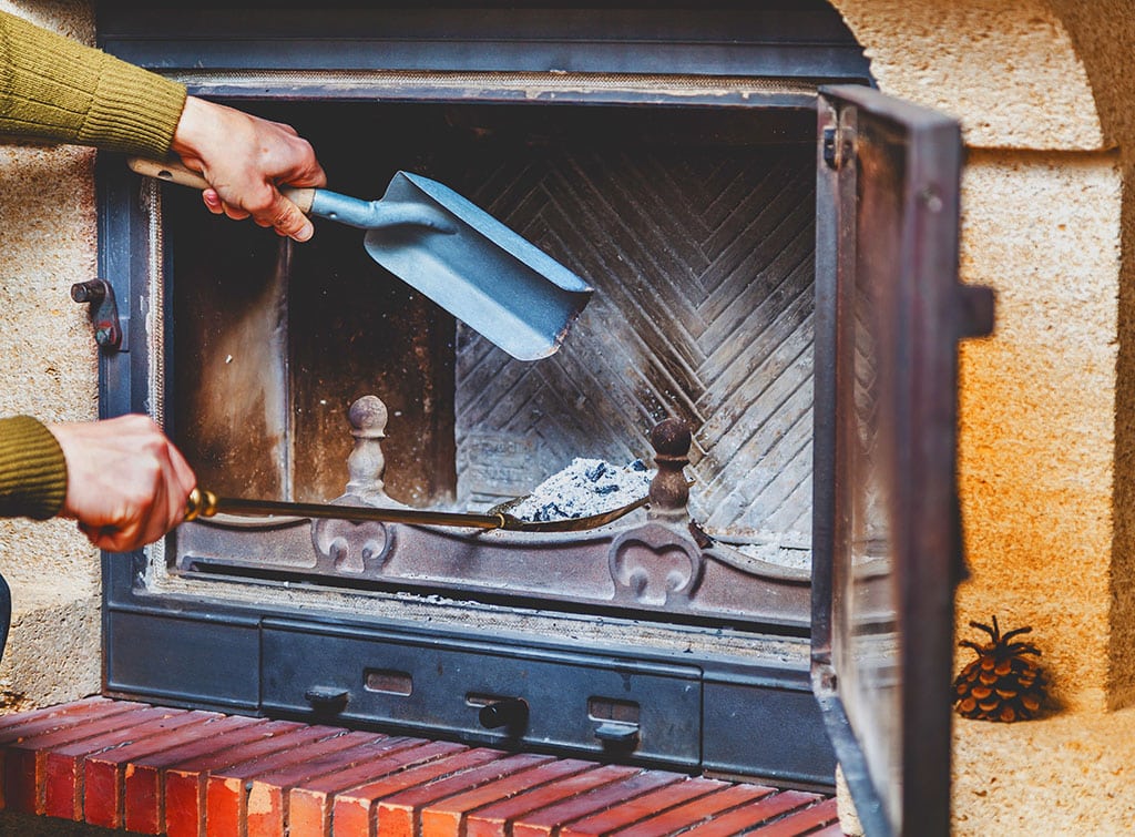 Cleaning fireplace. man pours ashes of blades