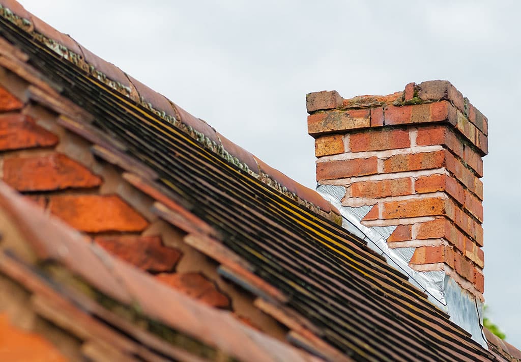 Damaged chimney needs repair old rooftop building exterior