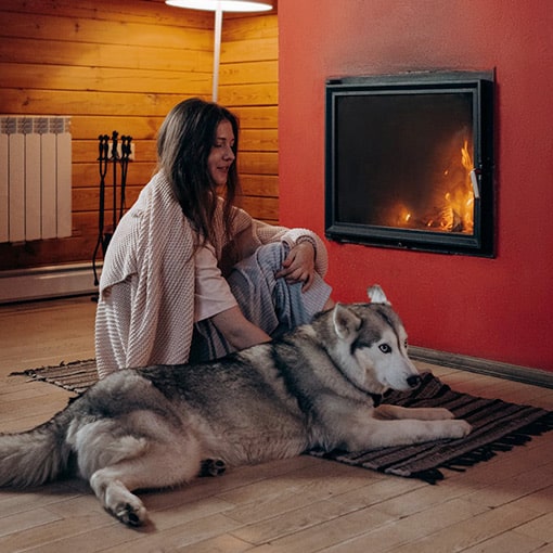 Fireplace with Lady and Dog sitting on a rug that is NOT fire safe.