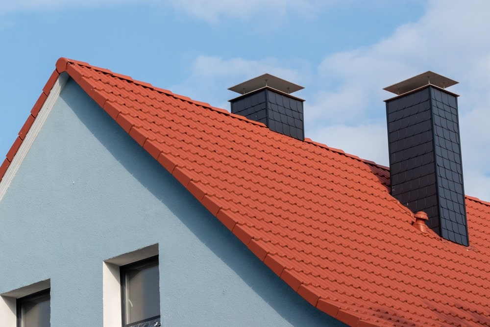 modern chimneys on blue house with red roof