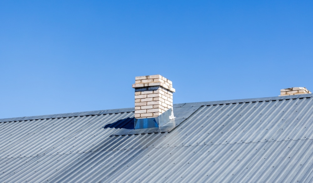 White chimney made of bricks is on a rural house roof